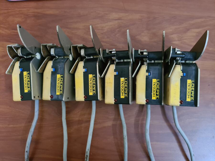 Row of yellow Loepfe electronic yarn clearer heads with cables laid out on a workbench