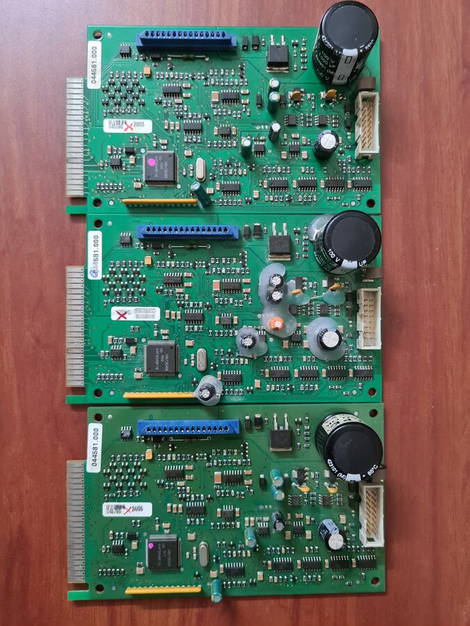 Three green electronic boards with large capacitors side by side